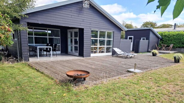 A modern house with a large deck, a fire pit, and outdoor seating. - 4 Star Holiday Home in Karrebaeksminde (Karrebæksminde)