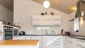 A modern kitchen with white cabinetry, stainless steel appliances, and a wooden countertop. - 4 Star Holiday Home in Karrebaeksminde (Karrebæksminde)