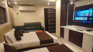 Habitación de hotel con dos camas, un sofá, un televisor y un minibar.