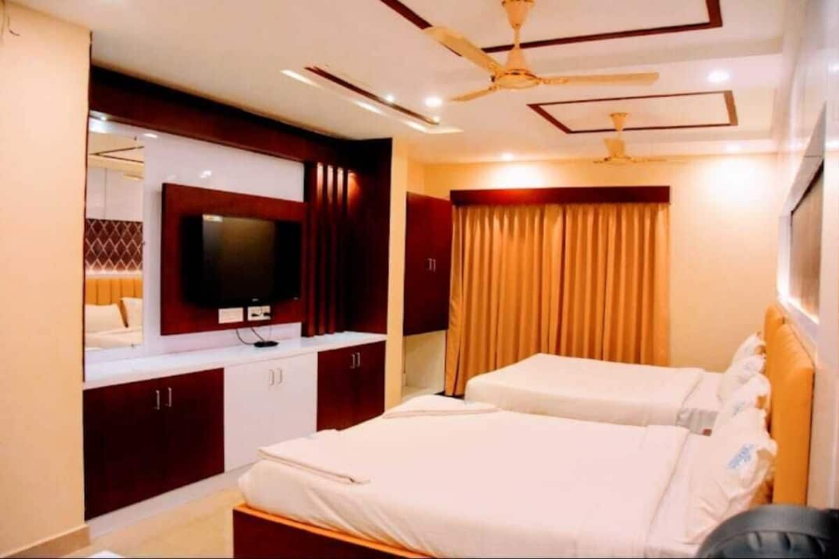 Habitación de hotel con dos camas, un televisor y un ventilador de techo.