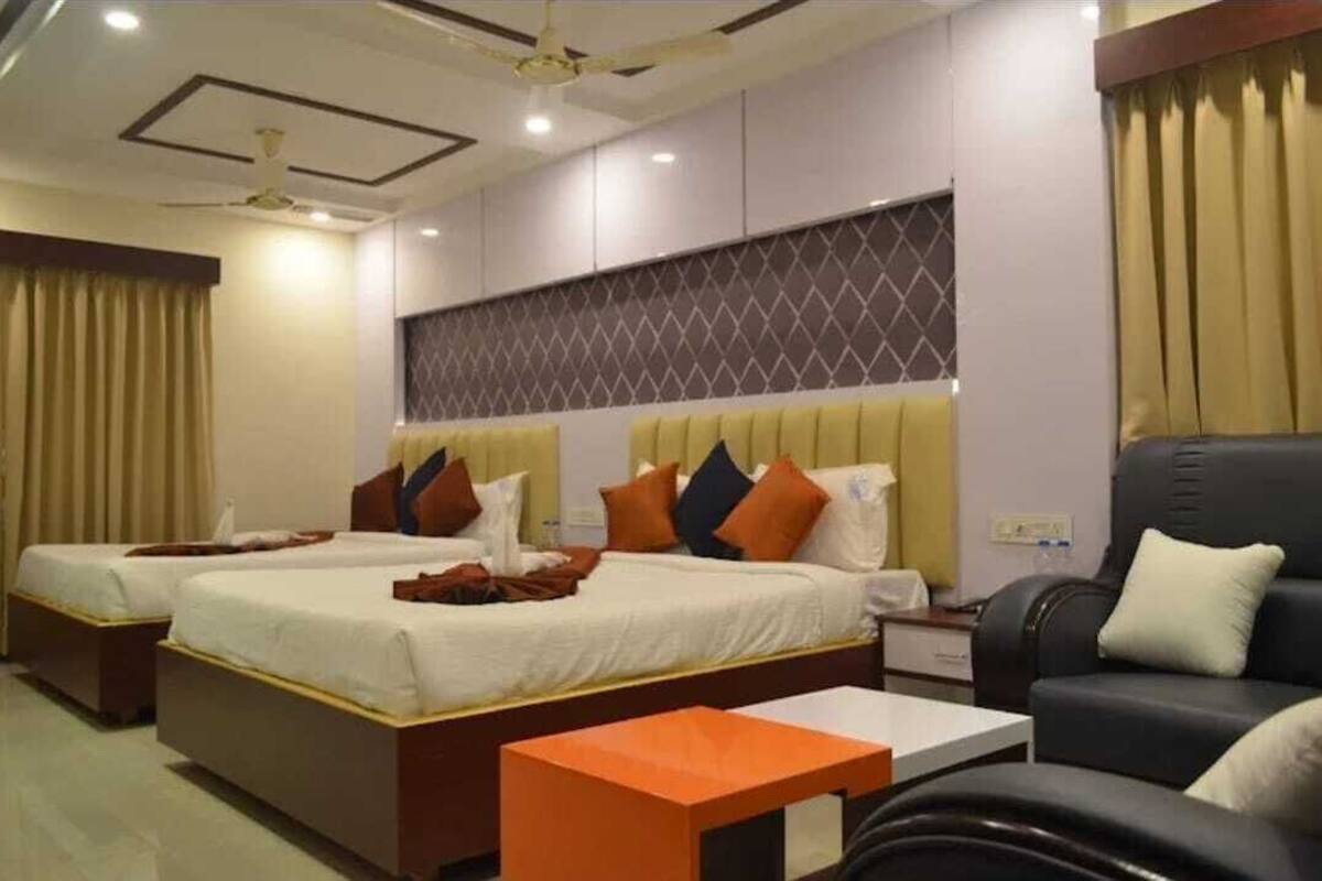 Habitación de hotel con dos camas, un sofá, una mesita y un ventilador de techo.