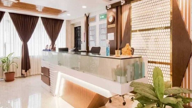 Un área de recepción con mostrador de vidrio, un reloj y un panel decorativo en la pared.