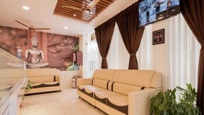 Una sala de estar moderna con un sofá, un televisor montado en la pared y una estatua de Buda en la pared.