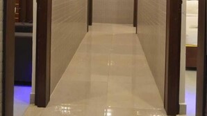 Un pasillo con suelo de baldosas y puertas de madera, que conduce a un área de baño.
