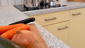 A kitchen with white tiled walls, a granite countertop, and a wooden cutting board with vegetables. - Appartment with beautiful mountain view (San Giorgio)