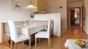 A dining area with a table set for four, a bench, and a fruit bowl on the table. - Appartment with beautiful mountain view (San Giorgio)
