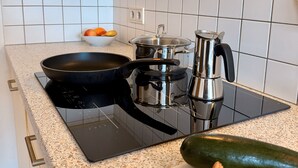 A kitchen with a black induction cooktop, a kettle, and a bowl of fruit on the counter. - Appartment with beautiful mountain view (San Giorgio)