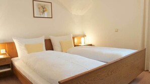 A double bed with a wooden frame and white bedding, a bedside table with a lamp, and a framed picture on the wall. - Appartment with beautiful mountain view (San Giorgio)