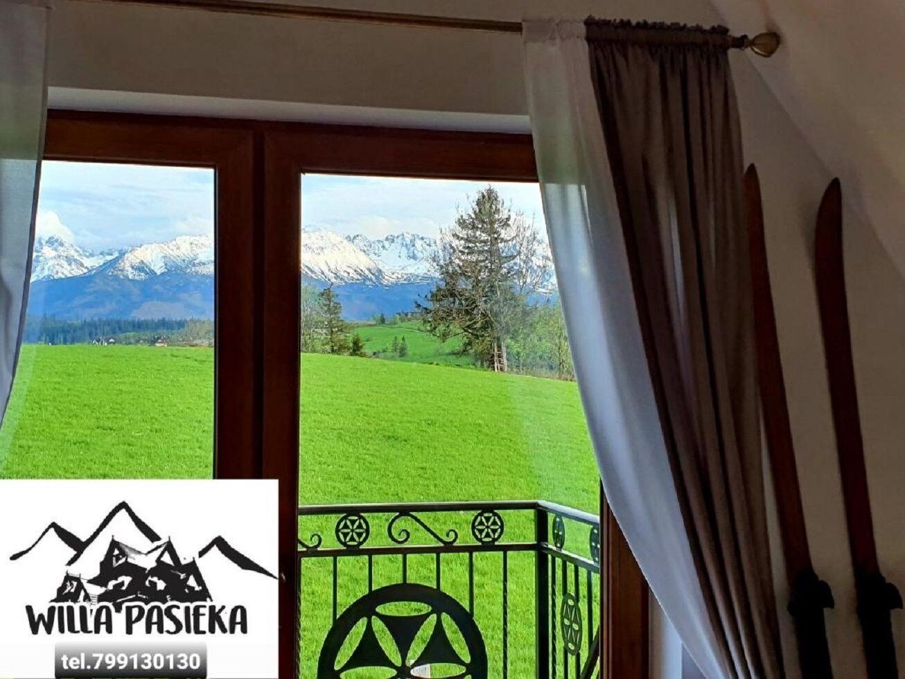 Habitación con vistas a montañas nevadas y un campo verde.