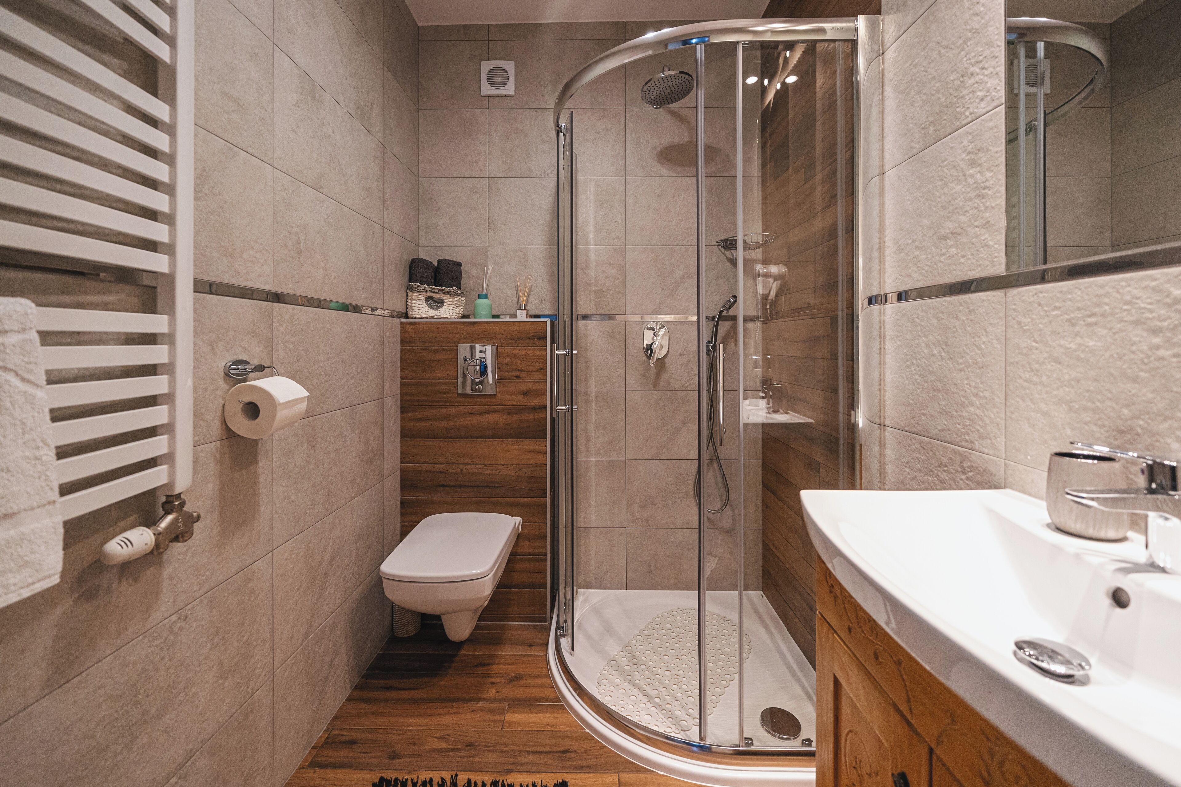 Une salle de bain moderne avec une douche à parois de verre, un meuble-lavabo en bois et des toilettes.