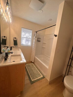 Une salle de bain équipée d’un lavabo, d’un miroir, d’une douche et de toilettes.