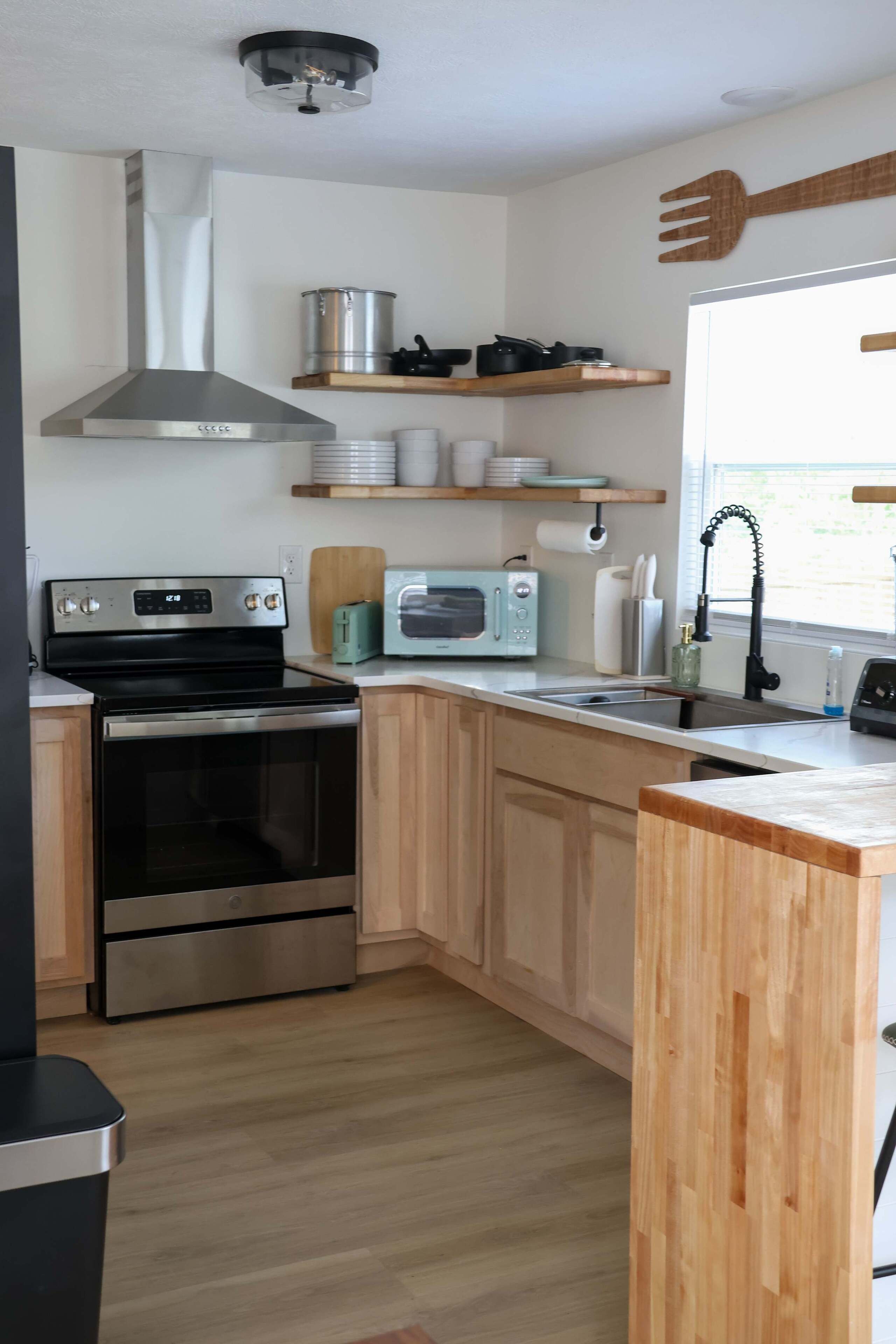 A modern kitchen with stainless steel appliances, wooden cabinets, and a window with a view.
