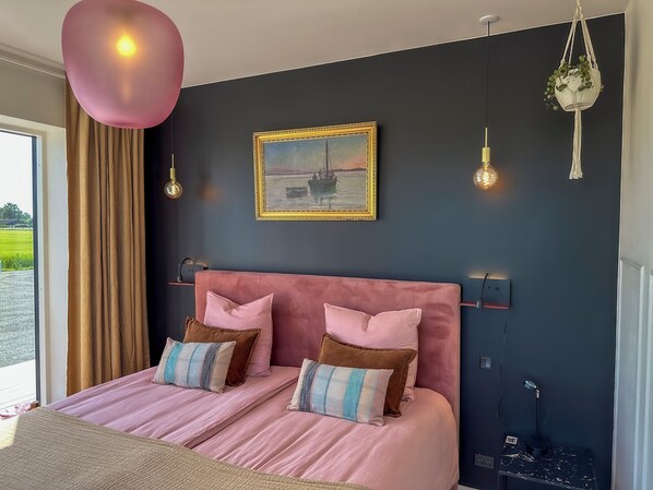 A bedroom with a large bed, a painting, and a view of the outdoors. - Seaside Retreat & Hotel (Stege)