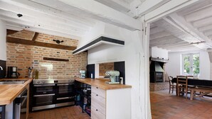 Una cocina con pared de ladrillo, encimera de madera y hornos empotrados.