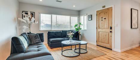 A modern living room with a grey sectional sofa, a round coffee table, and a wooden door.