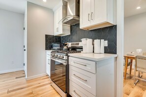 Uma cozinha moderna com armários brancos, painel de backsplash hexagonal preto e eletrodomésticos de aço inoxidável.