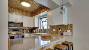 A kitchen with white cabinets, a granite countertop, a built-in microwave, and a large window. - Mtn Views & Canyon Access: Cottonwood Heights Home (Salt Lake City)