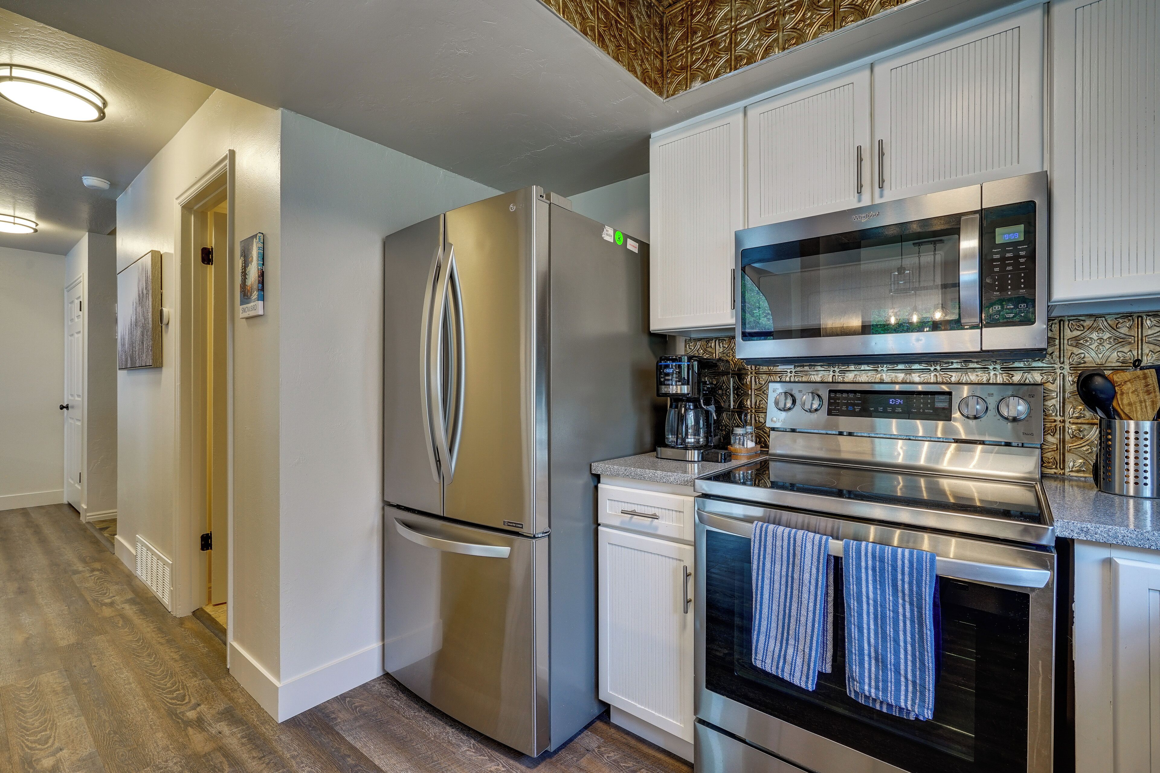 Una cocina moderna con electrodomésticos de acero inoxidable, armarios blancos y un salpicadero decorativo.
