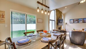 A dining area with a wooden table set for six, surrounded by chairs, with a large window providing a view of the outdoors. - Mtn Views & Canyon Access: Cottonwood Heights Home (Salt Lake City)