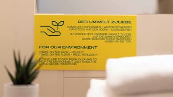 A yellow sign with text in German and English about towel reuse for environmental benefits.