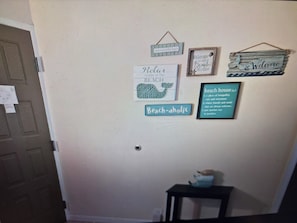 A wall with various signs and decorations, including a 'Welcome' sign, a 'Beach House' sign, and a 'Beach-Aholic' sign.