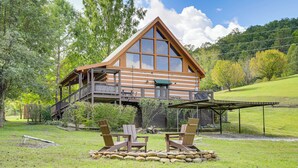 Una cabaña con terraza, mobiliario exterior y un hogar de piedra.