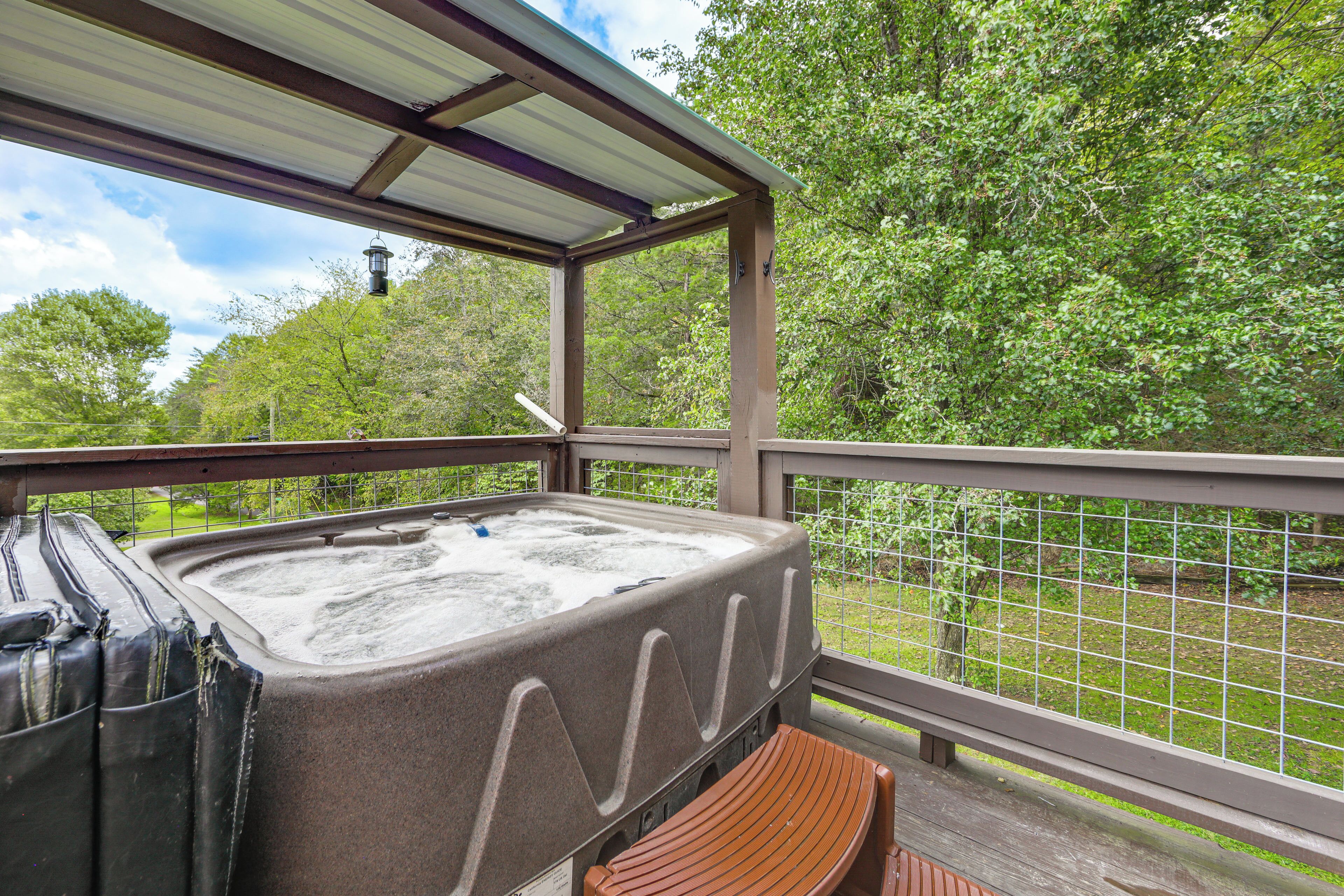 A hot tub on a covered deck with a view of trees.