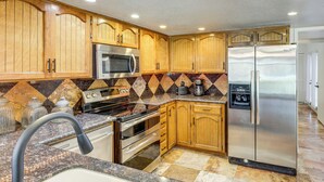 A kitchen with wooden cabinets, stainless steel appliances, a granite countertop, and a patterned backsplash. - 5 Mi to Colorado River: Yuma Gem w/ Pool Access! (Yuma)