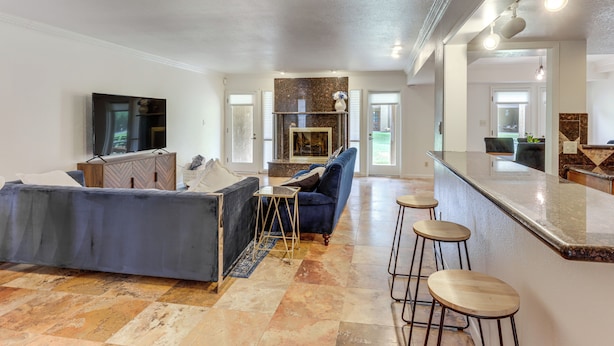 A spacious living area with a sofa, a TV, a fireplace, and a kitchen area with stools. - 5 Mi to Colorado River: Yuma Gem w/ Pool Access! (Yuma)