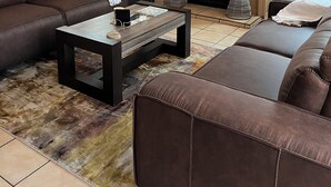 A living room with a brick fireplace, leather sofas, a coffee table, and a patterned rug. - Soothing 4-bedroom house in Manzini (Manzini)