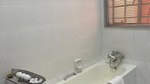 A bathroom with a bathtub, a hand soap dispenser, and a black mat on the floor. - Soothing 4-bedroom house in Manzini (Manzini)