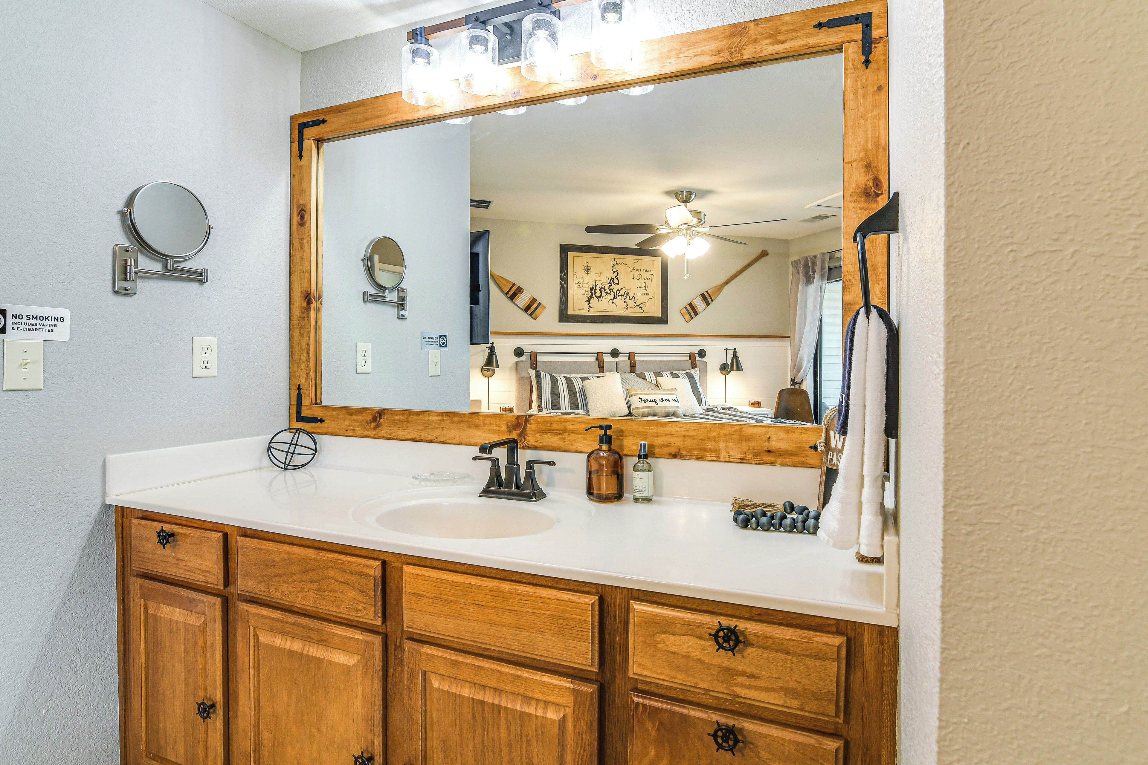A bathroom with a wooden vanity, a large mirror, and a ceiling fan.