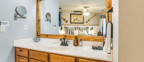 A bathroom with a wooden vanity, a large mirror, and a ceiling fan.