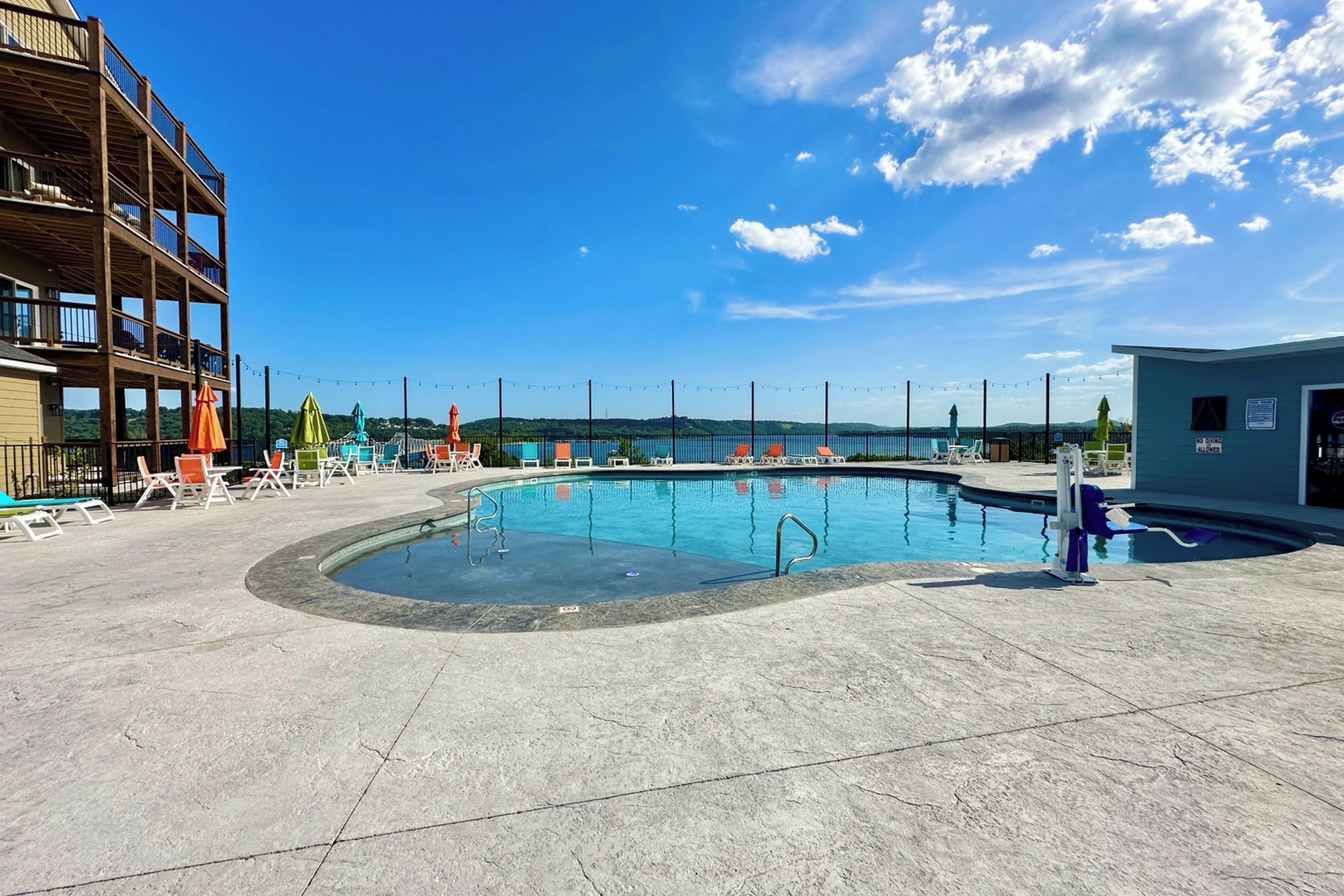 Piscina con sillas de descanso y vista a un cuerpo de agua.