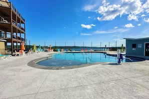 Piscina con sillas de descanso y vista a un cuerpo de agua.