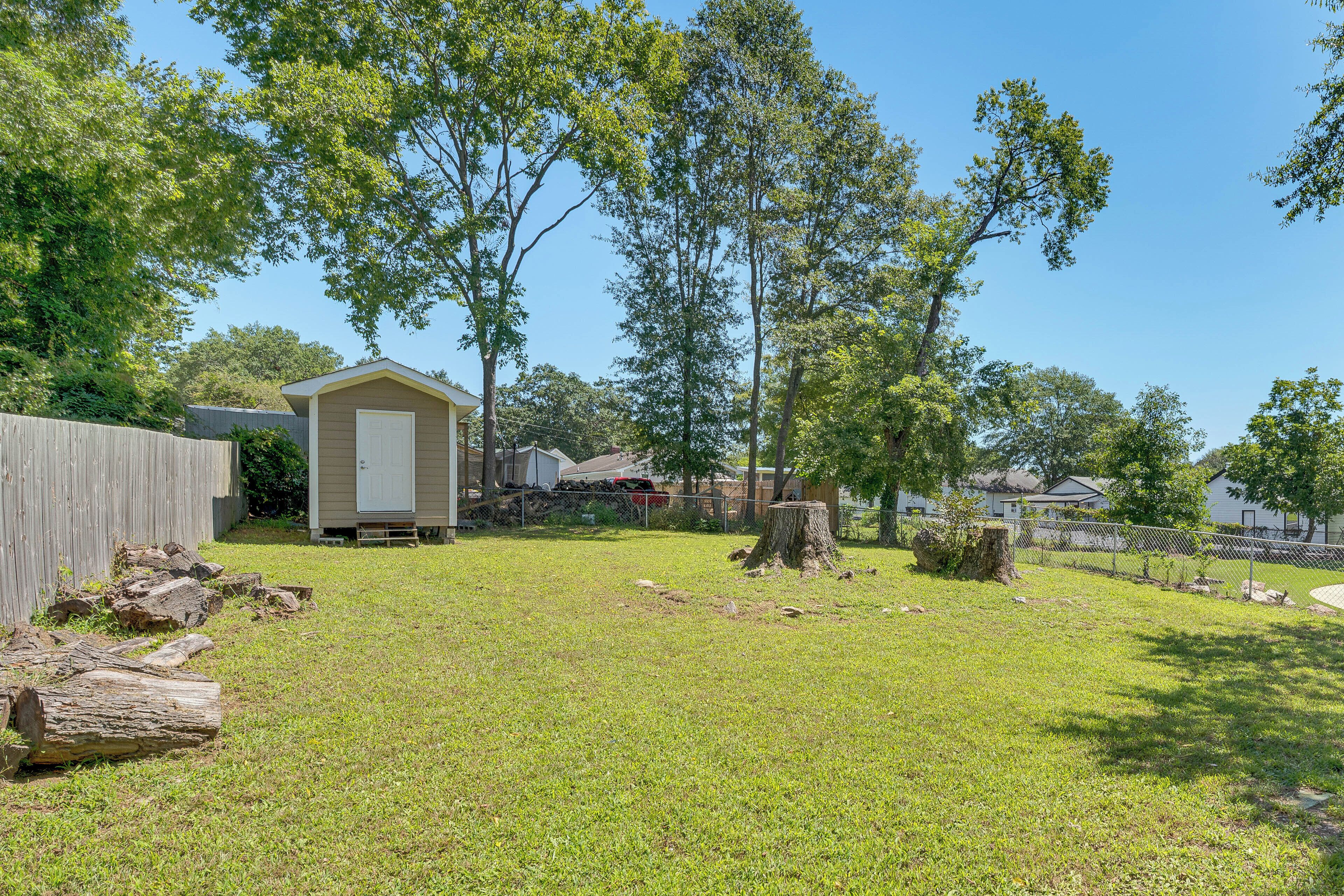 A backyard with a shed, a tree stump, and a wooden fence.