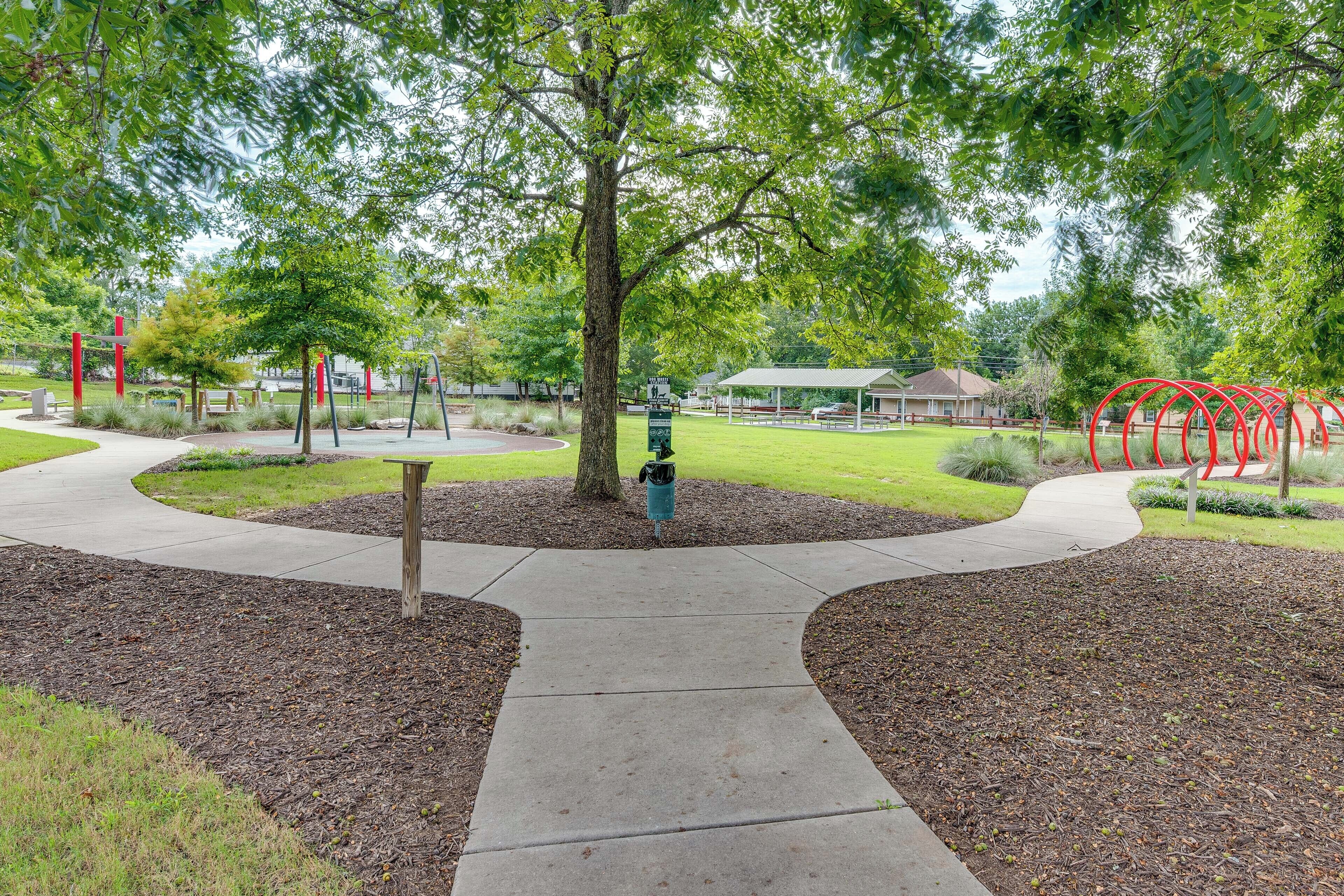 A park with a central tree, a playground, and a gazebo.