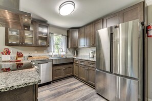 A modern kitchen with stainless steel appliances, granite countertops, and wooden cabinets. - Steps to Playground: Family Home in Douglasville! (Douglasville)