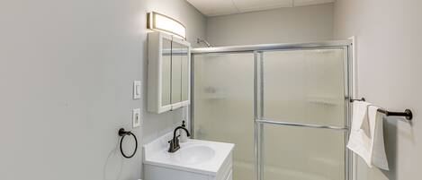A bathroom with a toilet, sink, and frosted glass shower enclosure.