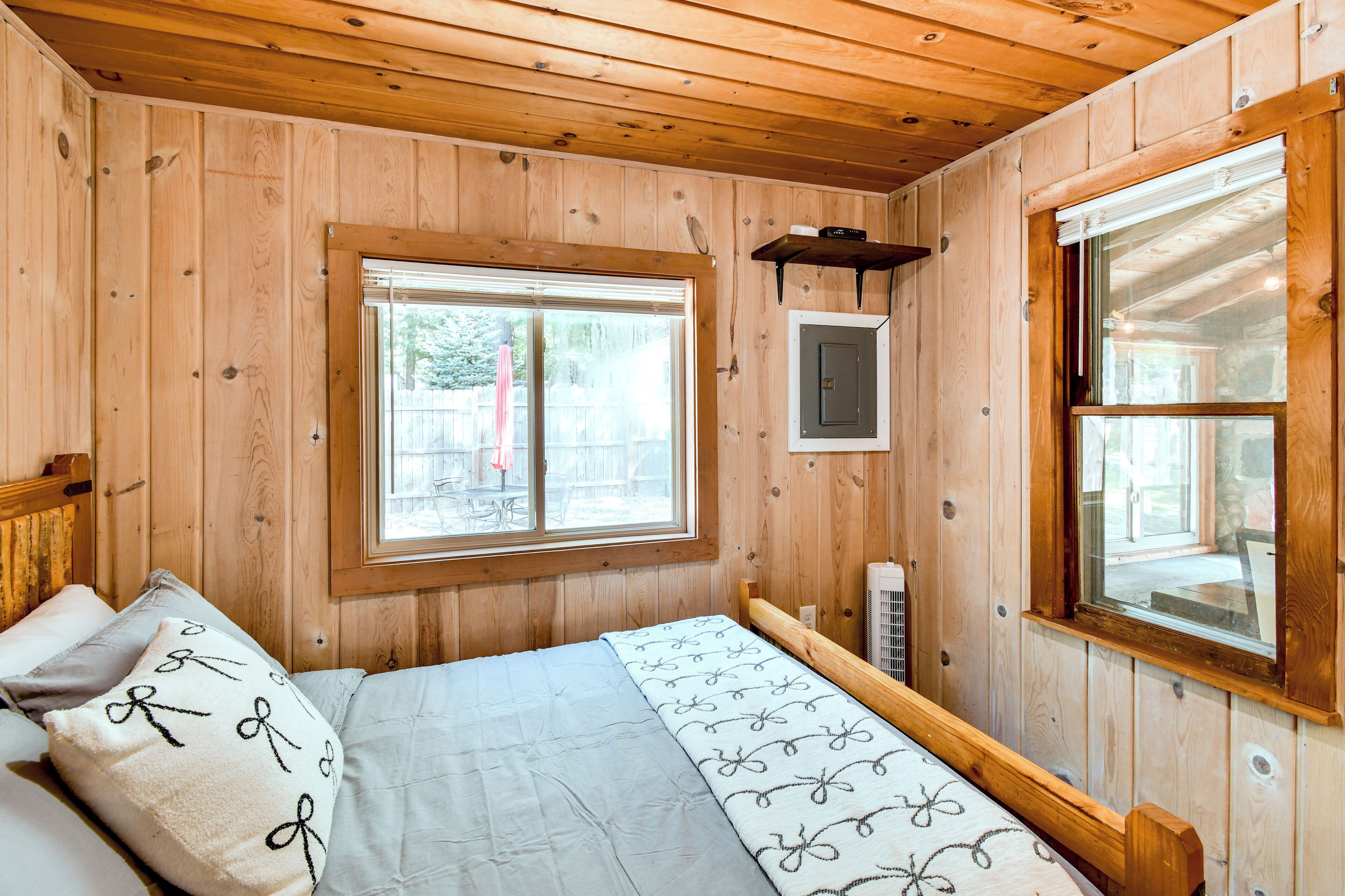 Una habitación de cabaña de madera con una cama, una ventana y un calentador.