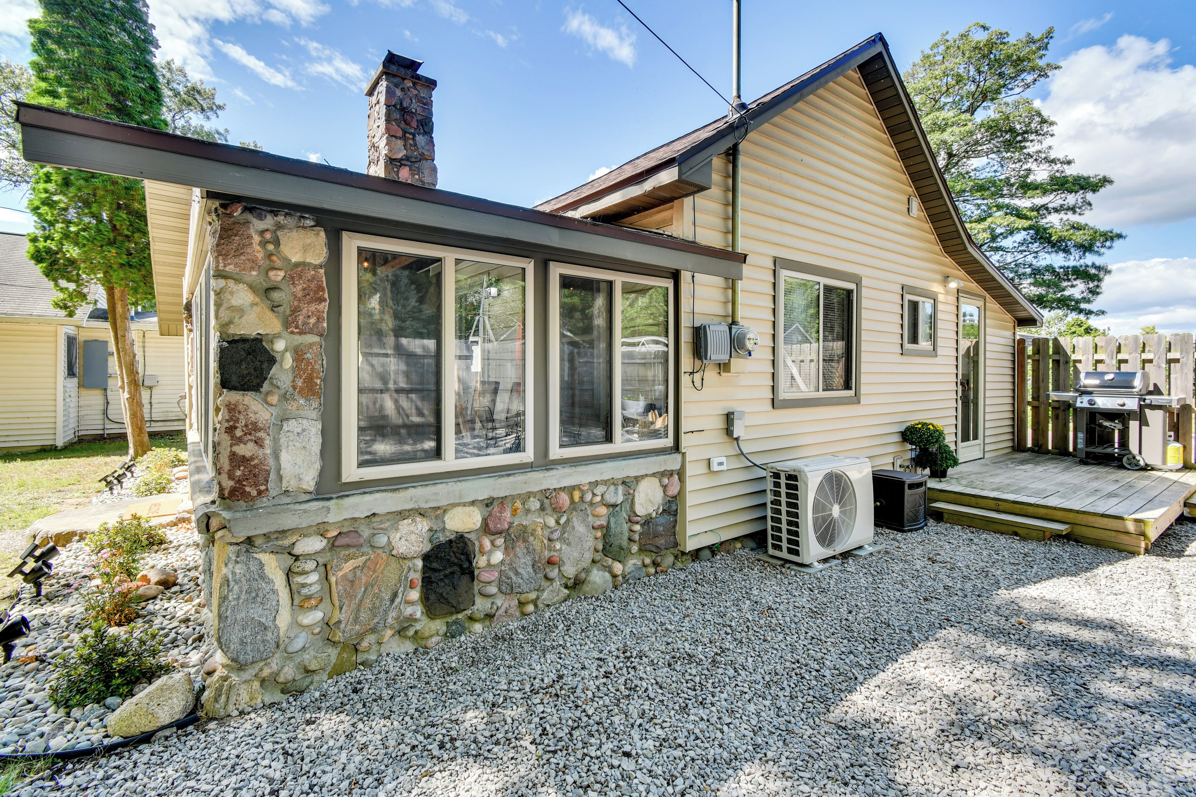 A single-story house with a stone foundation, large windows, and a covered porch.