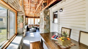 A rustic interior with exposed wooden beams, stone walls, and a wooden dining table with fruit. - Houghton Lake Cabin: 0.3 Mi to Beach & Pier! (Prudenville)