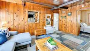 A wooden-floored living room with a sofa, a coffee table with a plant, and a fireplace. - Houghton Lake Cabin: 0.3 Mi to Beach & Pier! (Prudenville)