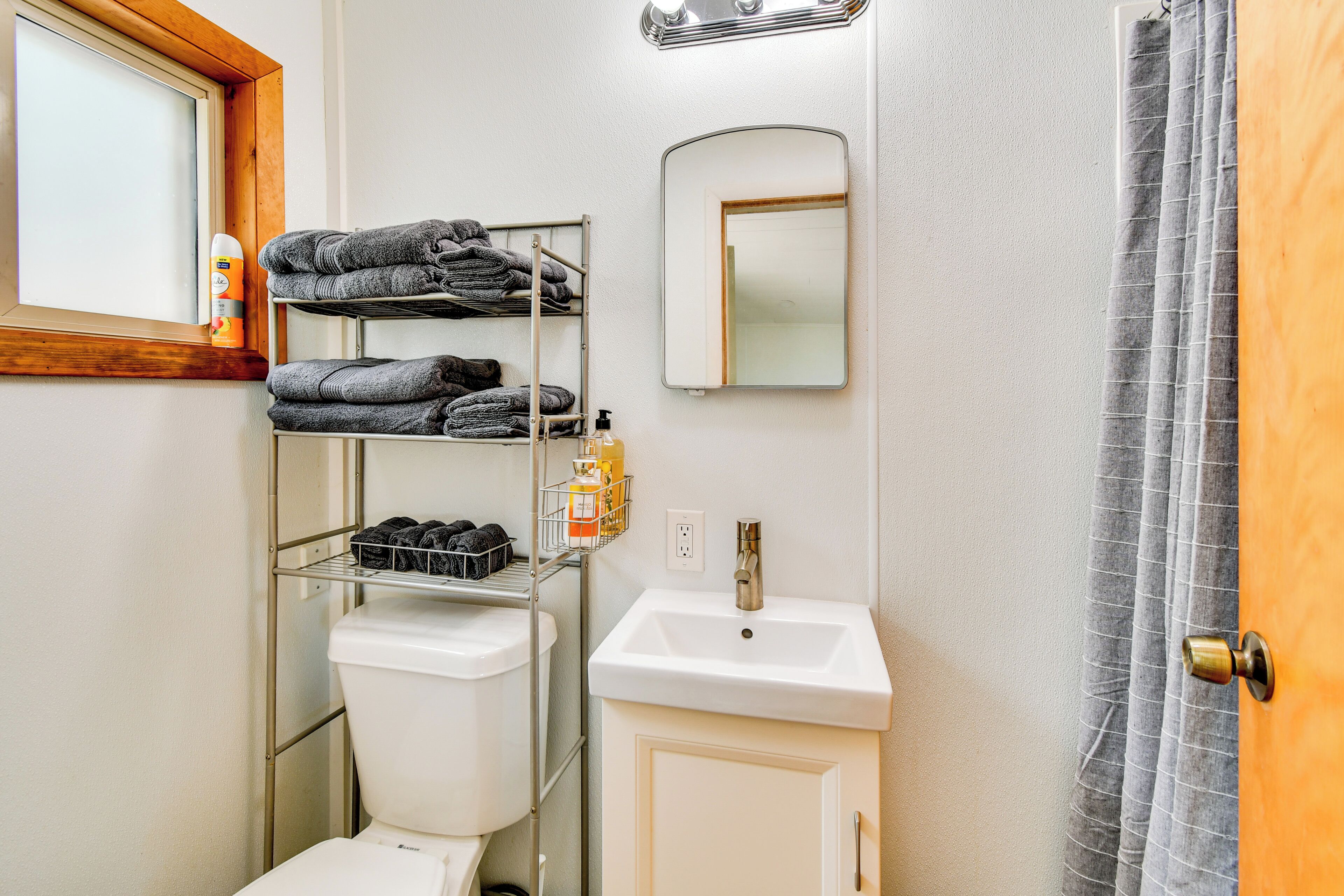 A bathroom with a toilet, a sink, a mirror, and a towel rack.