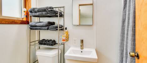 A bathroom with a toilet, a sink, a mirror, and a towel rack.