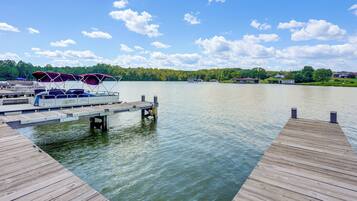 A wooden dock extending into calm water with boats docked at the end.