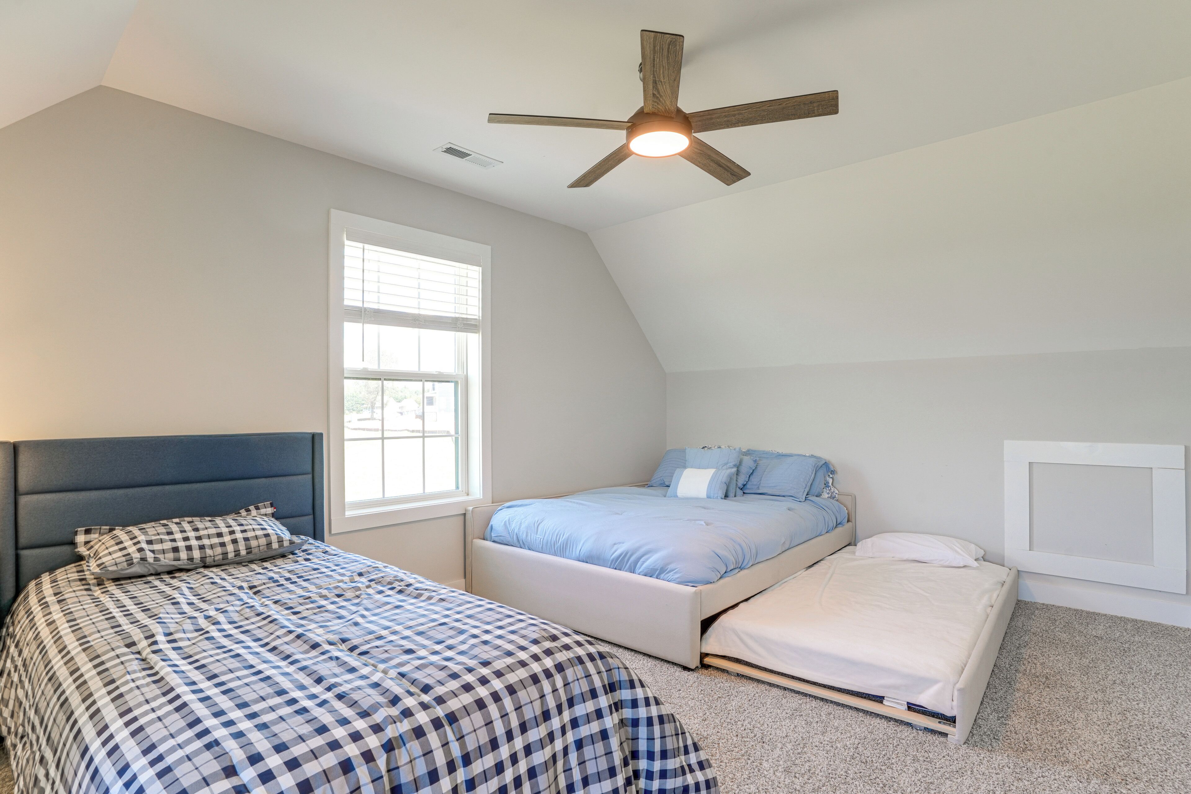 A bedroom with two beds, a ceiling fan, and a window.