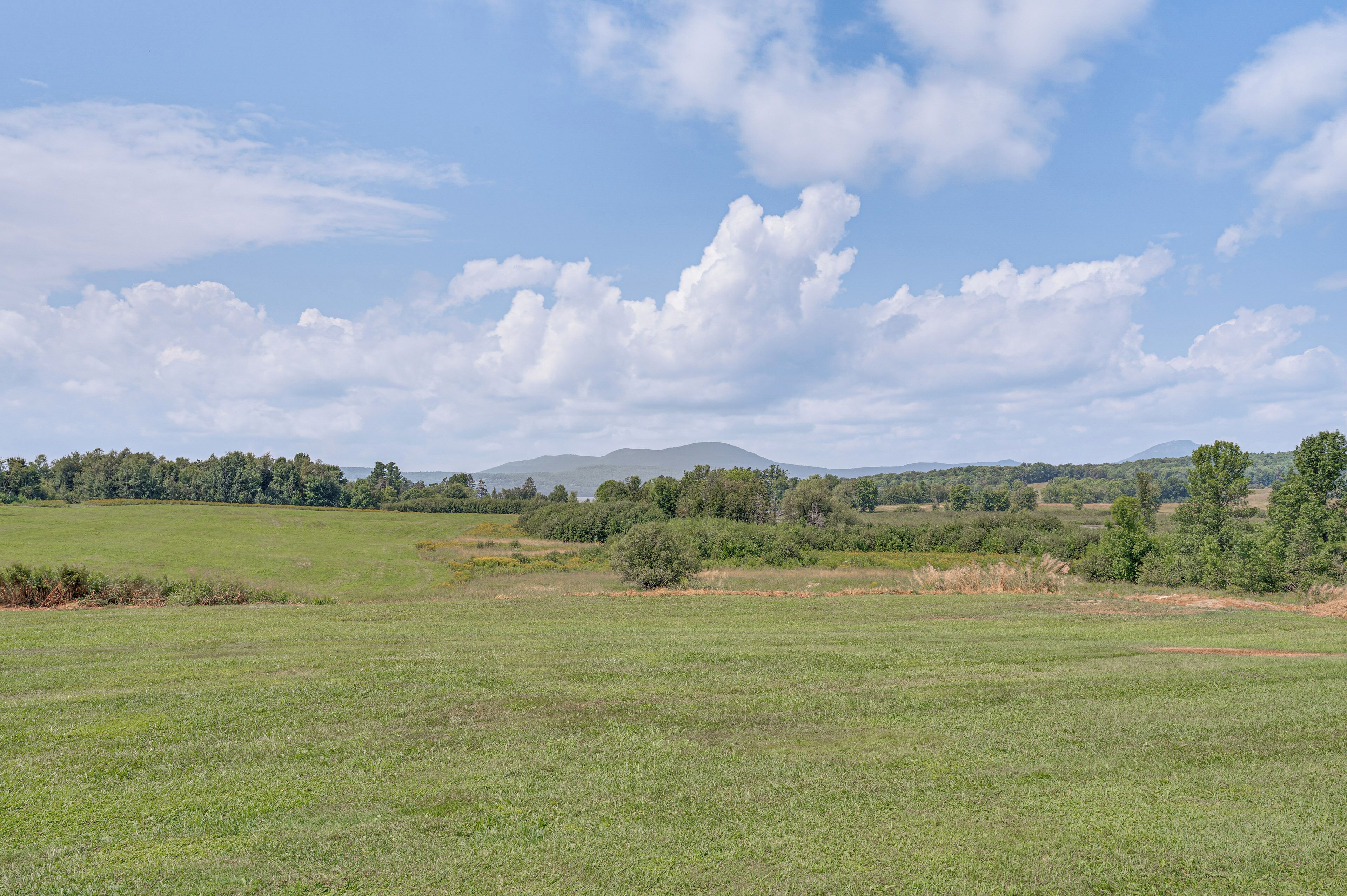 A wide, open field with a distant mountain range and a clear sky.