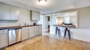 A modern kitchen with stainless steel appliances, white cabinetry, and a bar area with stools. - < 1 Mi to Lake: Mtn-view Cabin w/ Porch in Newport (Newport)