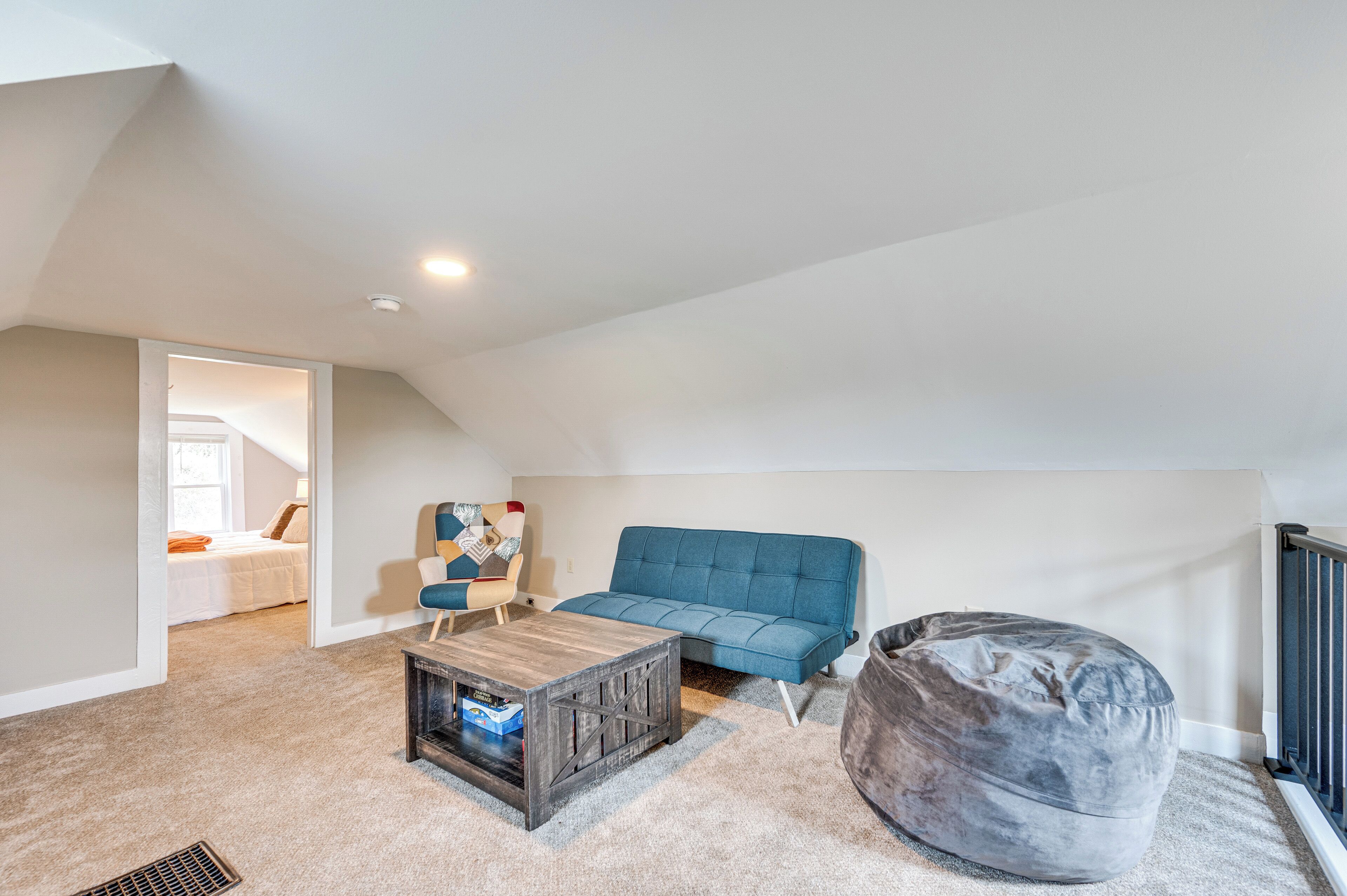 A loft-style living room with a blue sofa, a wooden coffee table, and a grey bean bag.